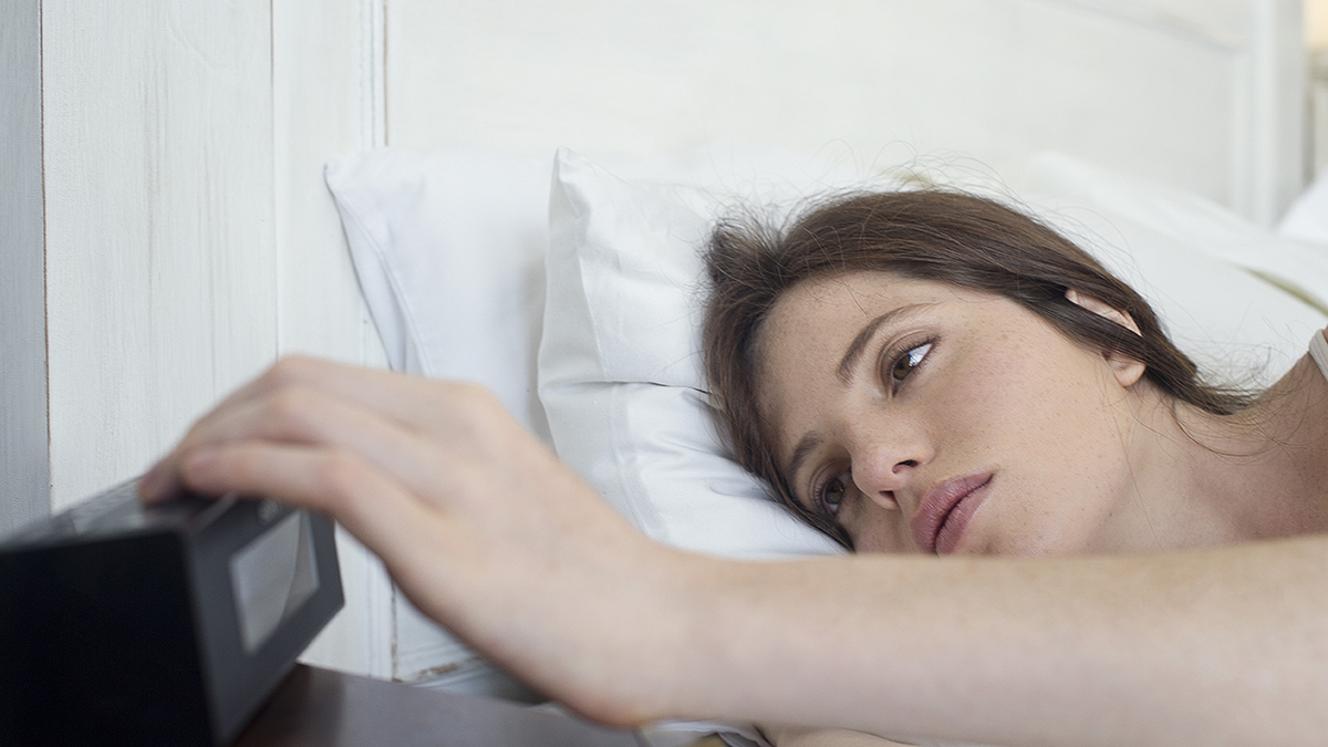 woman waking up and turning off her alarm