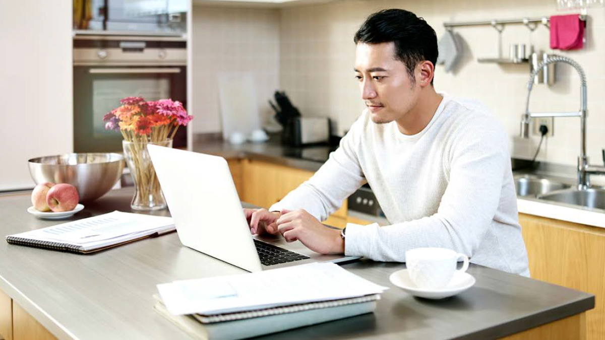 man working from home and looking at computer screen